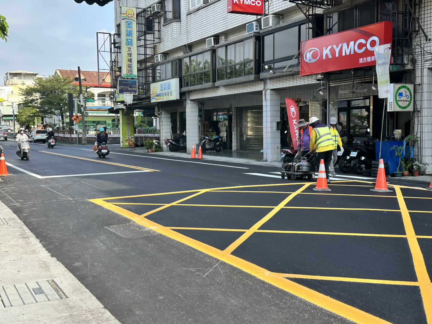 華興街新鋪柏油路面上，施工人員推著手推式熱熔標線機劃設標線