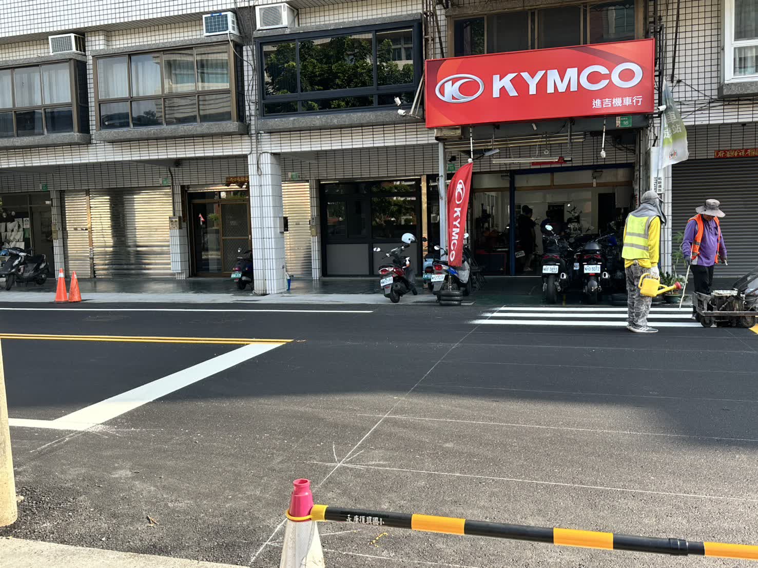 華興街新鋪柏油路面上繪設白色行人穿越道，施工人員以熱熔劃線機作業